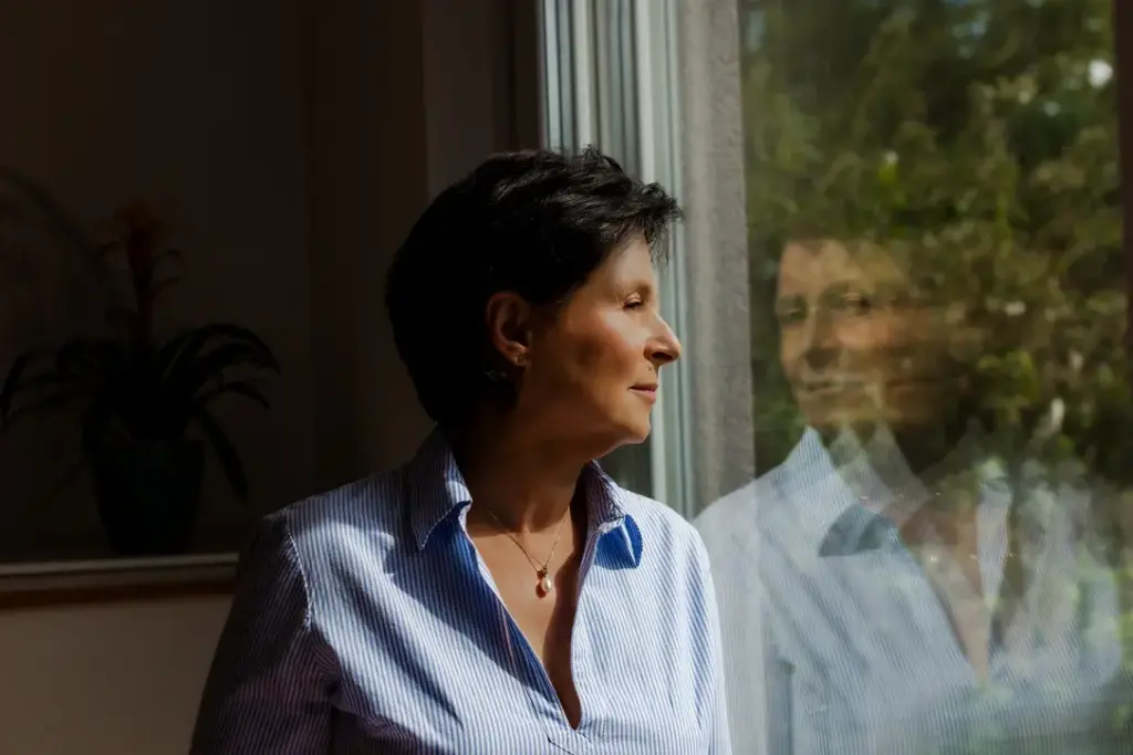 Seitliches Porträt einer Frau am Fenster mit Spiegelung in der Scheibe, passend zum Human Design Reflektor Thema Selbstwahrnehmung und innere Klarheit.