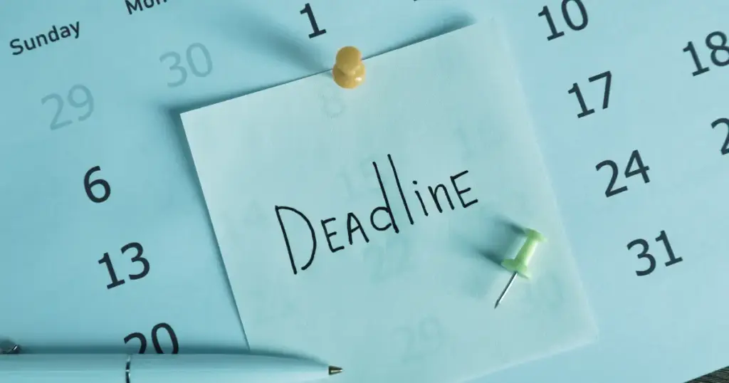 Notizzettel mit dem Wort „Deadline“ auf einem Kalender mit Reißzwecken befestigt