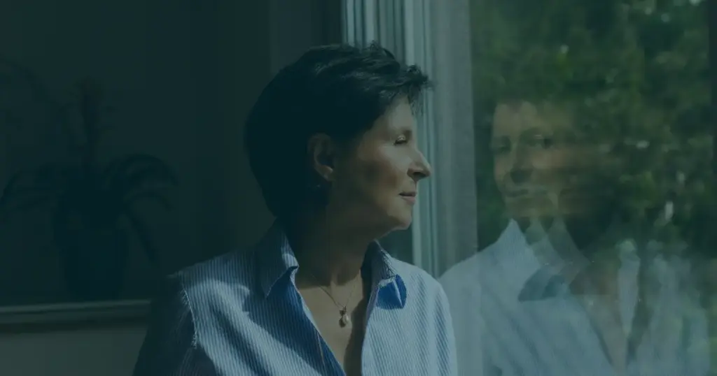 Seitliches Porträt einer Frau am Fenster mit Spiegelung in der Scheibe, passend zum Human Design Reflektor Thema Selbstwahrnehmung und innere Klarheit.