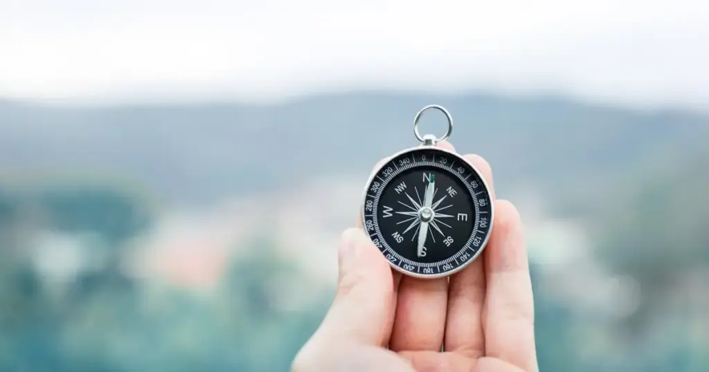 Kompass in der Hand vor unscharfem Hintergrund – Sinnbild für Orientierung durch die Mondautorität beim Reflektor im Human Design