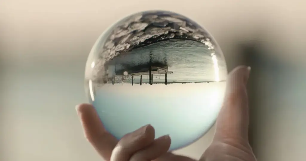 Hand hält Glaskugel mit gespiegelter Landschaft – Sinnbild für die veränderliche Wahrnehmung und Klarheit bei Reflektoren im Human Design